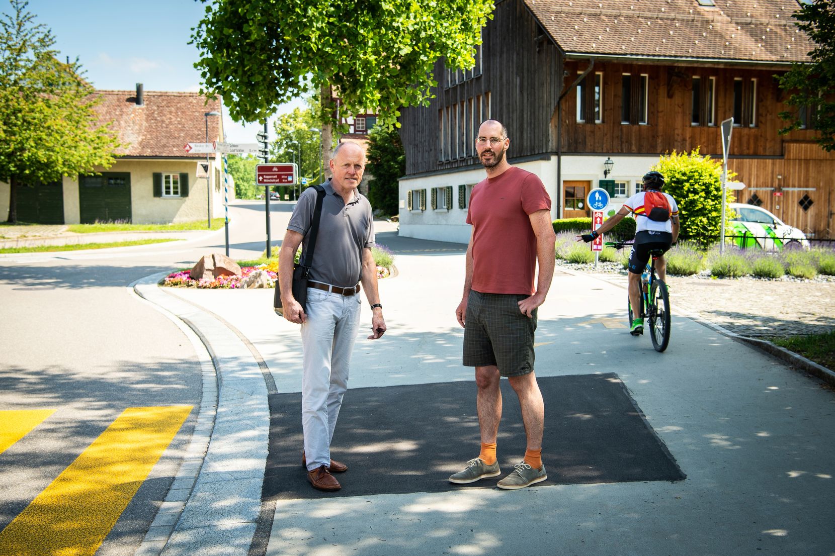 Zwei Männer stehen auf einem Trottoir neben einem Fussgängerstreifen.